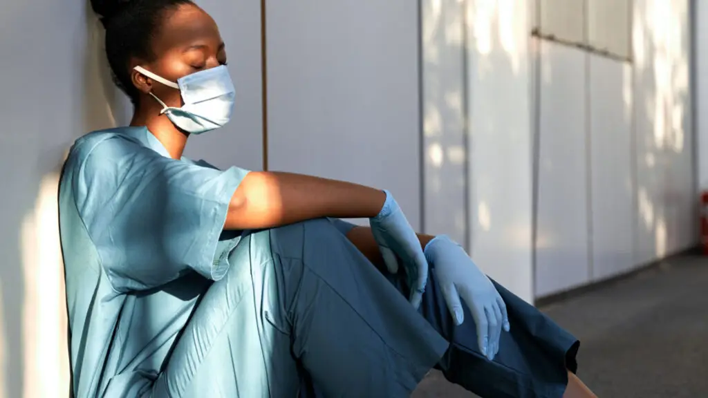 Tired nurse siting on the ground with back against the wall