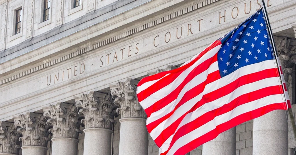 united states flag waives in front of building