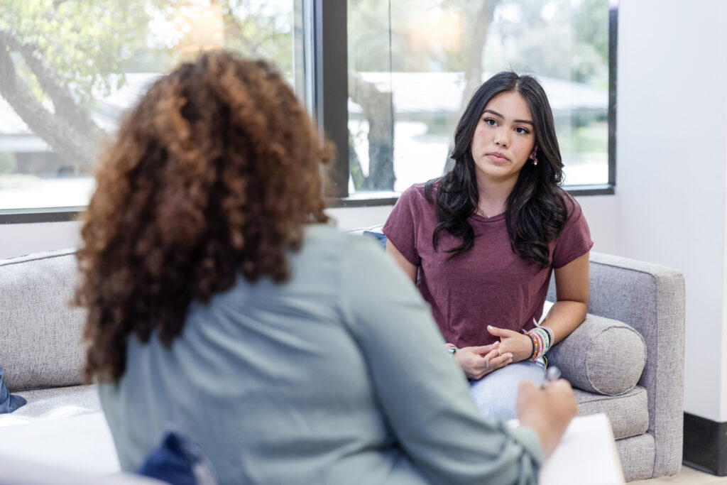 curly haired woman talking to her therapist in a well lit room