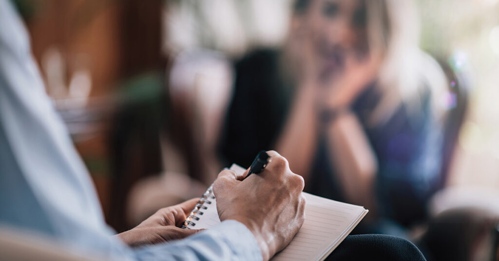 therapist writing notes as the client is consoling with him